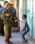Brave Jewish soldier points weapon at handcuffed Palestinian boy